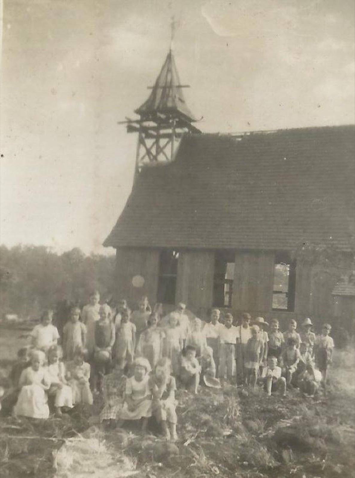 Grupo de crianças em frente à antiga capela de madeira