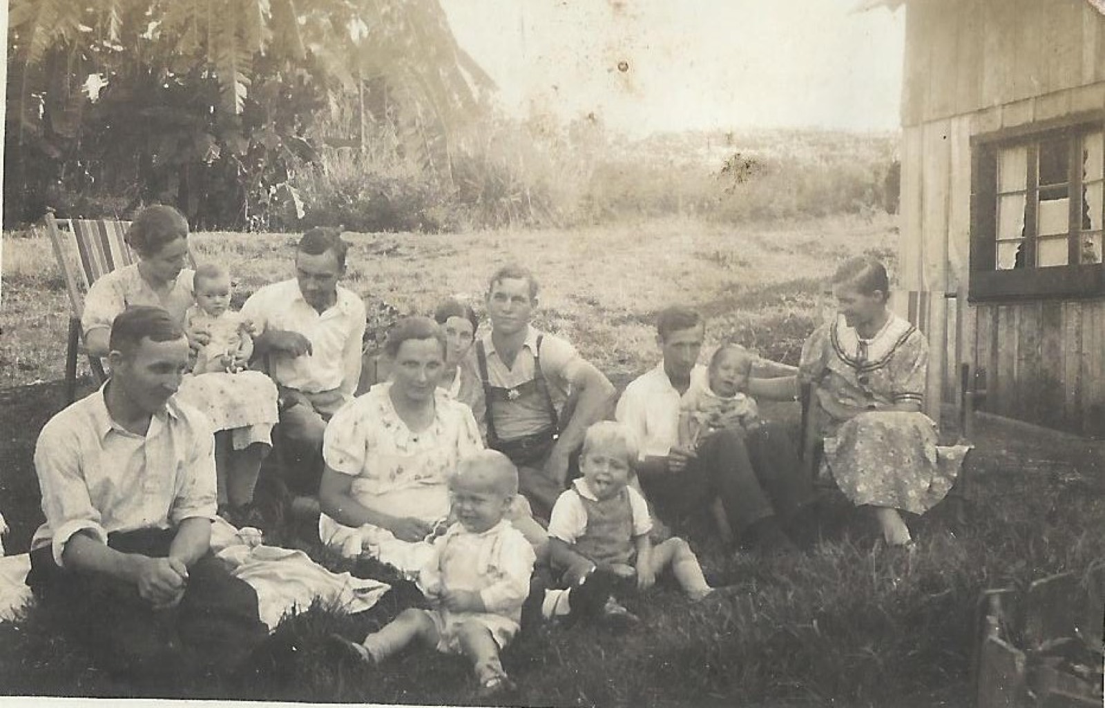 Famílias sentadas no gramado ao lado de uma casa de madeira, c.1940