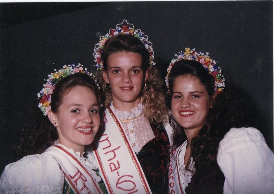 Três soberanas da Oktoberfest com coroas de flores e faixas