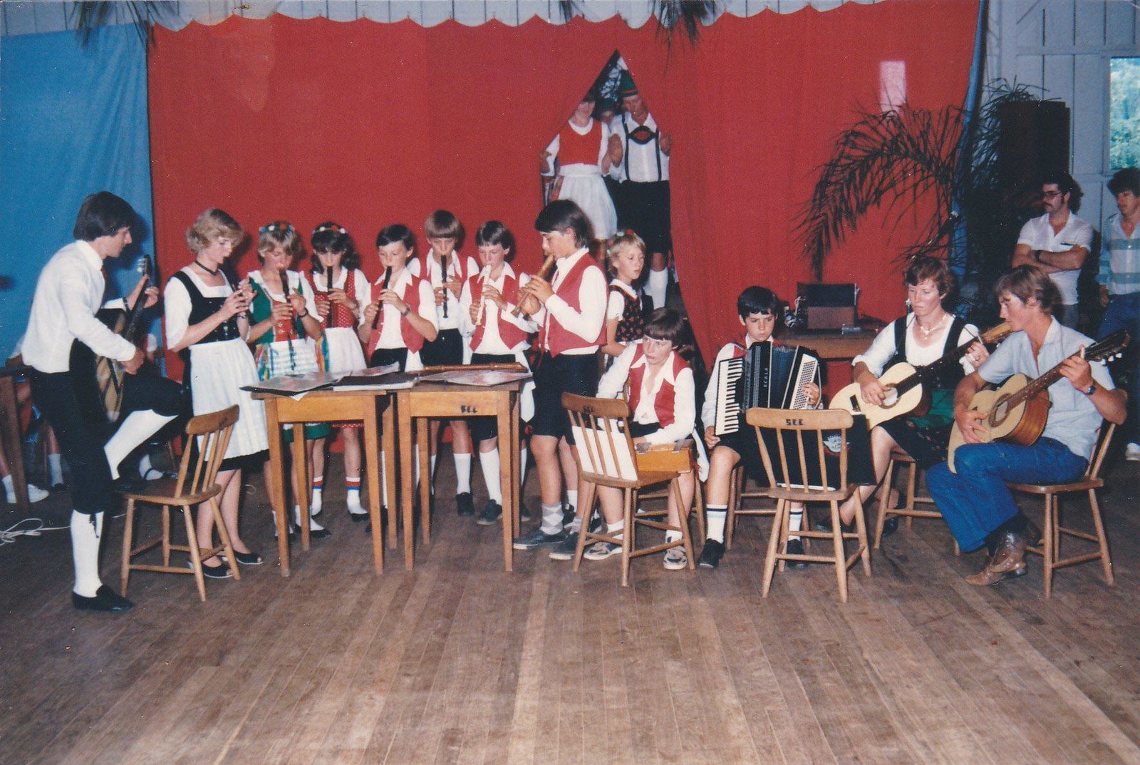 Banda e grupo infantil em trajes típicos no palco do salão