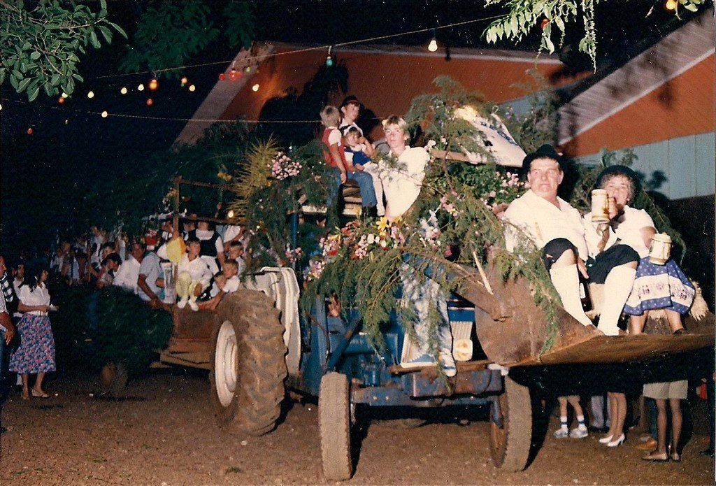 Trator e carroça enfeitados com folhagem em desfile noturno com público