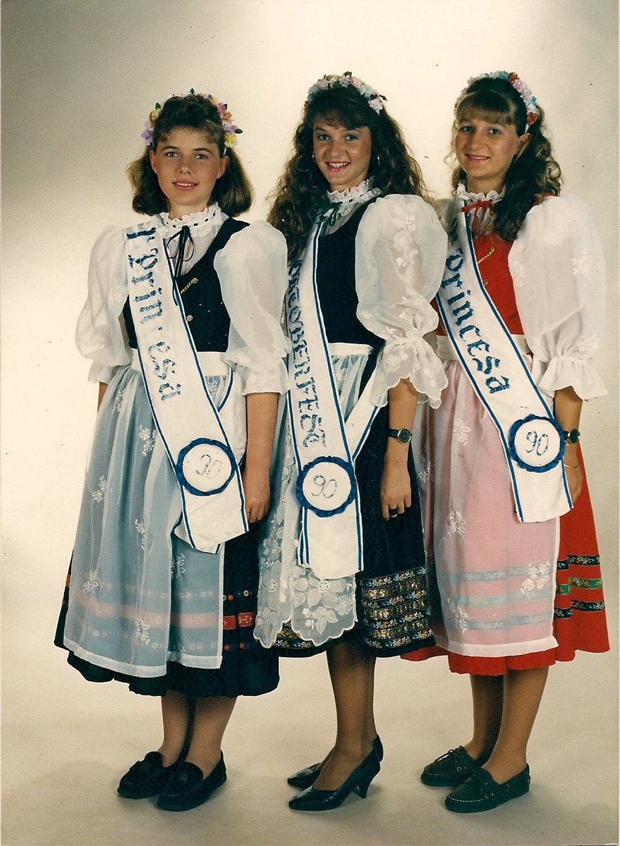 Três soberanas em trajes típicos azul, branco e vermelho