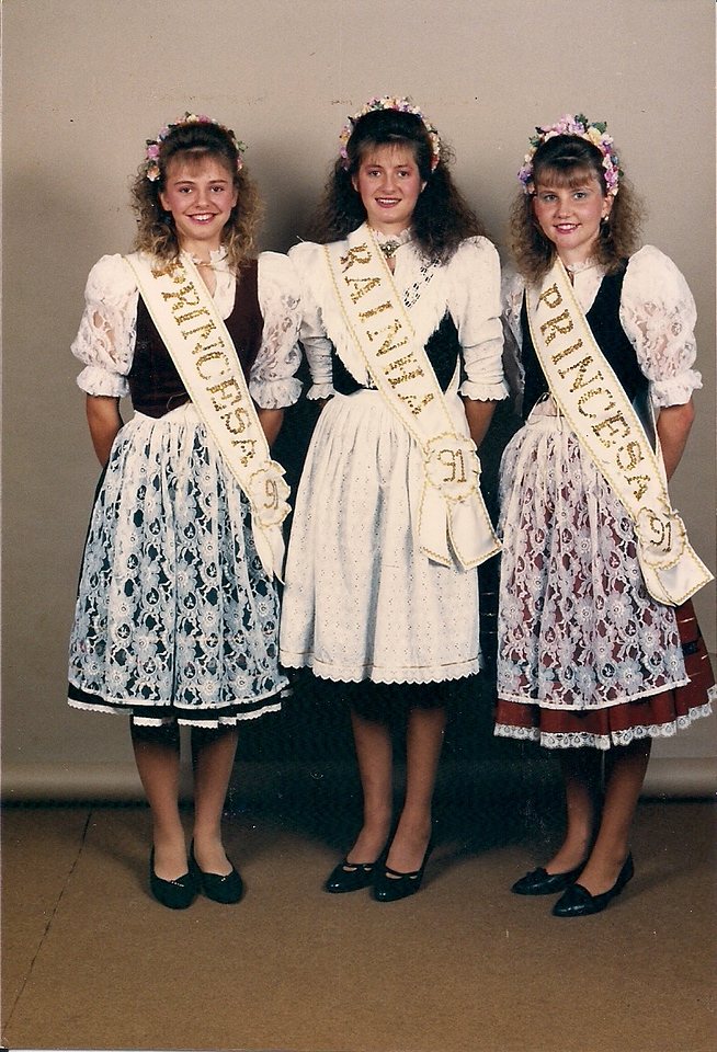 Três soberanas com vestidos típicos de renda e faixas