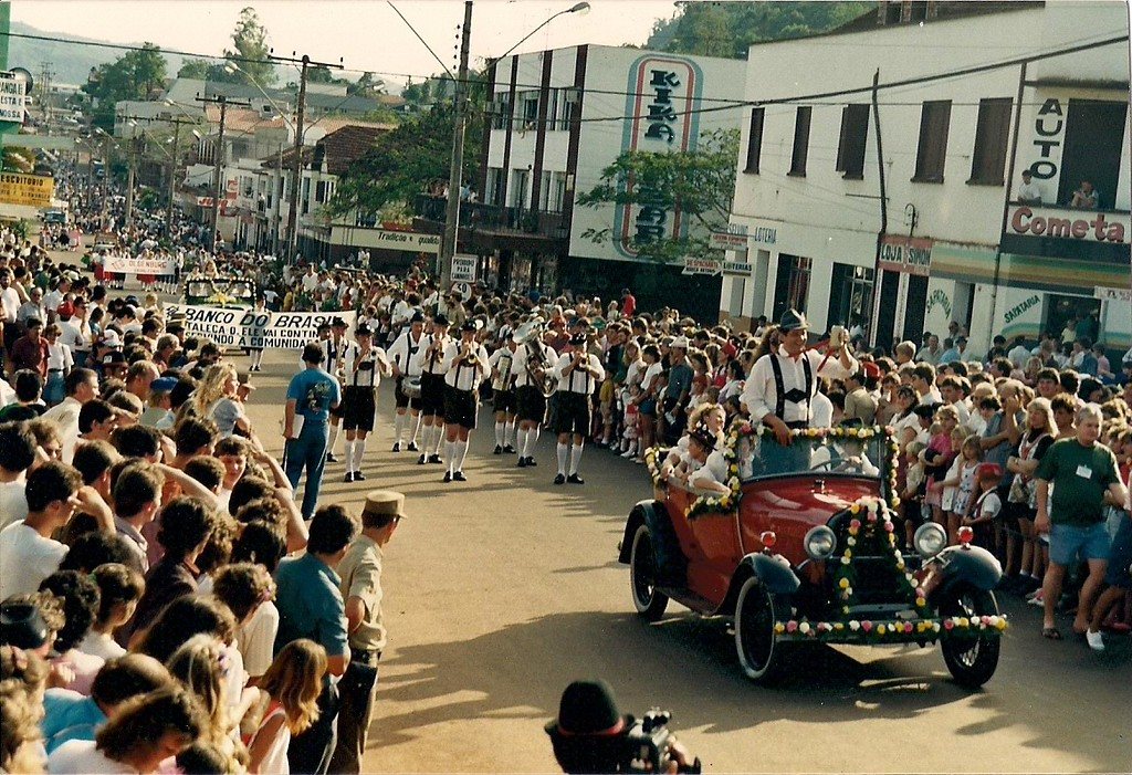Carro antigo desfilando entre a multidão na rua