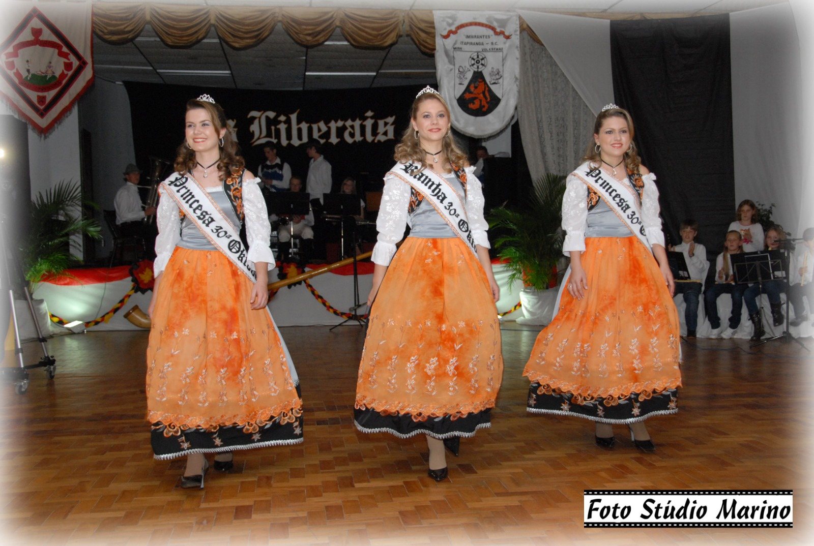 Soberanas no palco da coroação com vestidos laranja