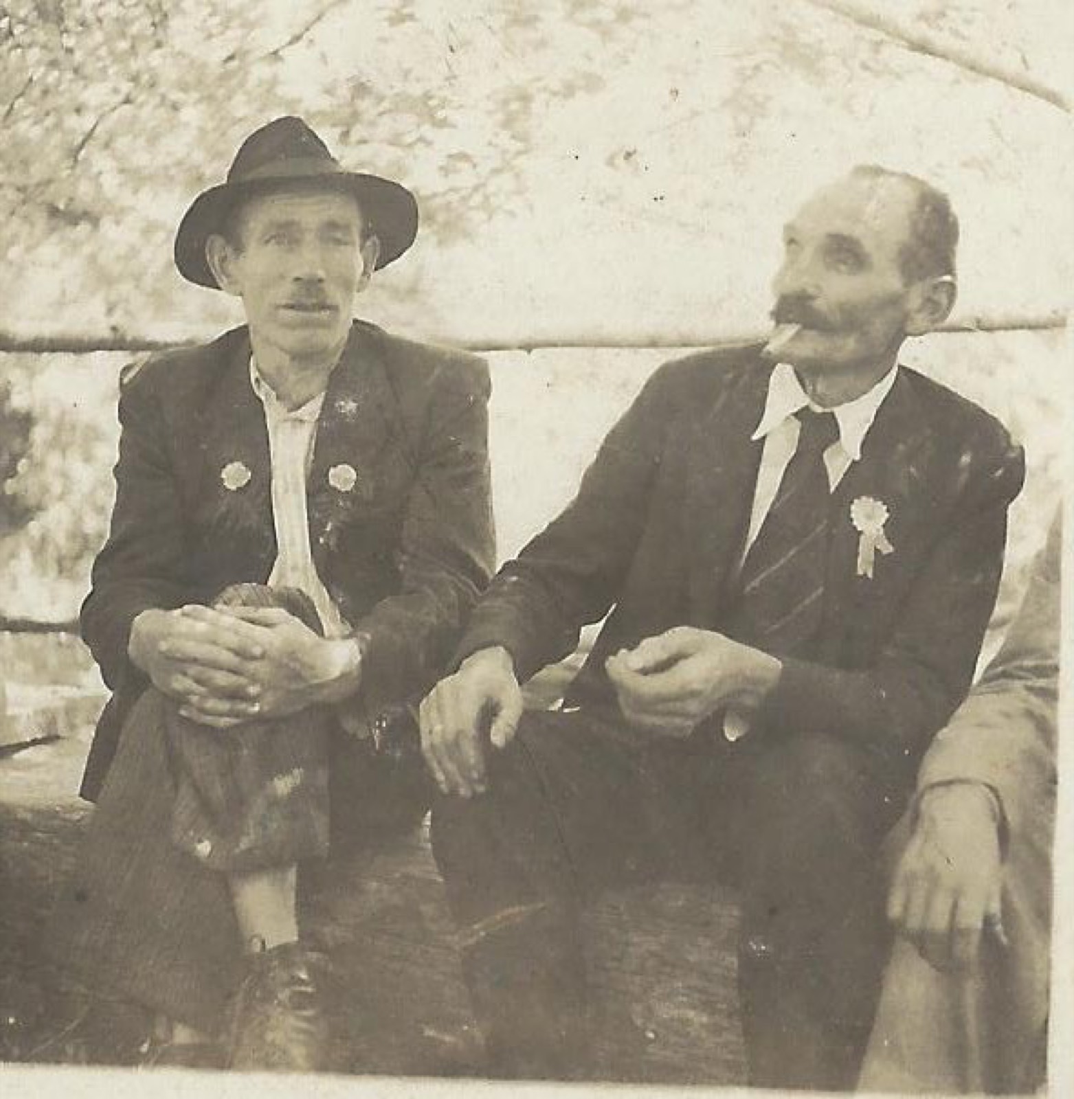 Dois homens de terno e chapéu com flores na lapela, retrato antigo