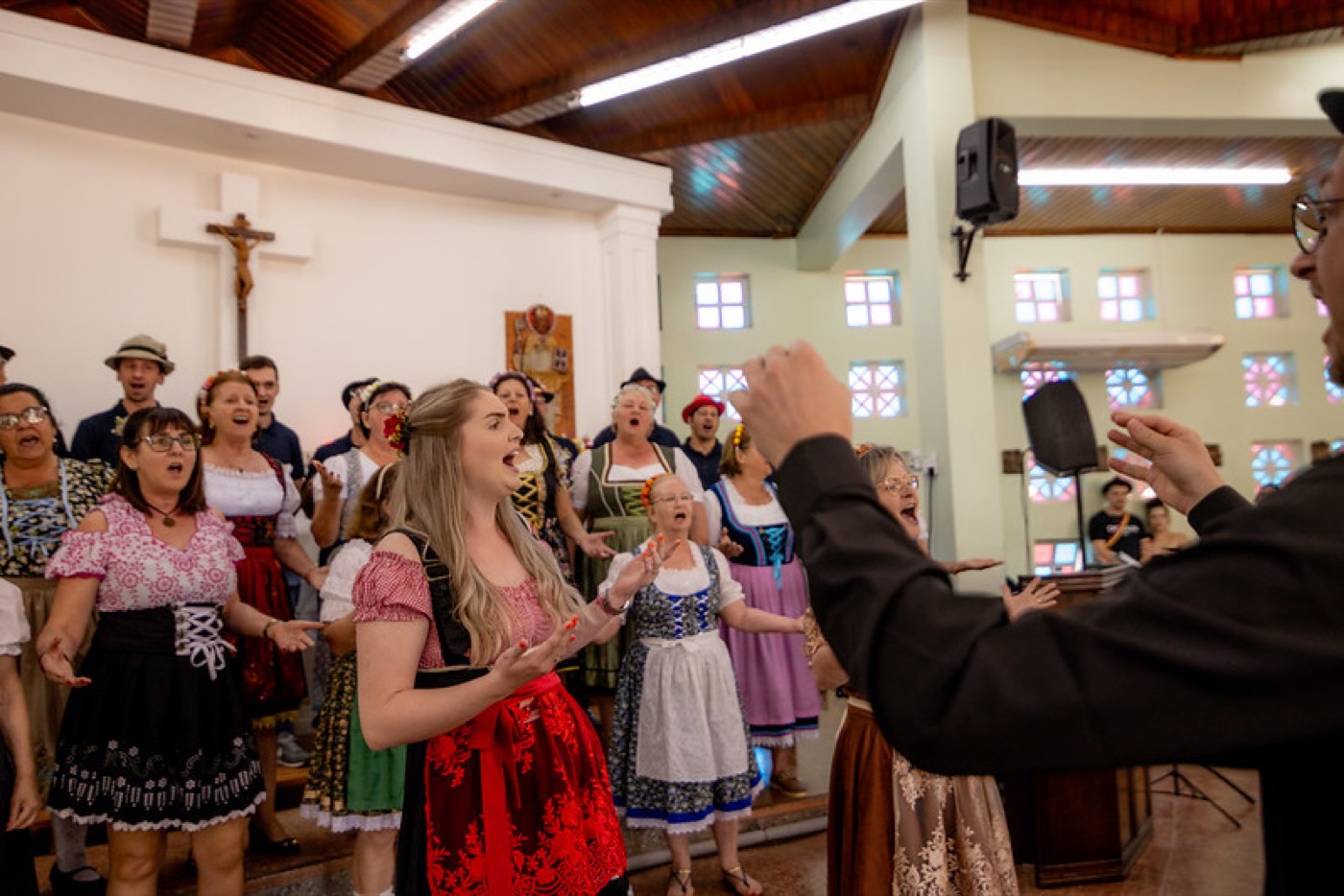 Coral cantando em trajes típicos sob a regência do maestro